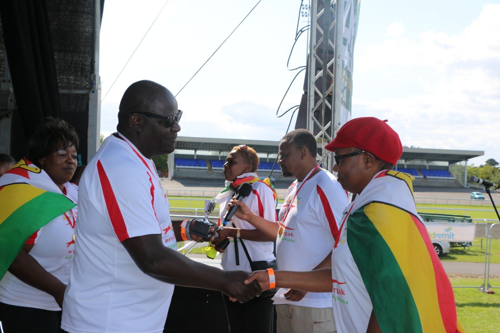 Salom gets her engraved cup from ZHRO Trustee Rev Canon Lameck Mutete